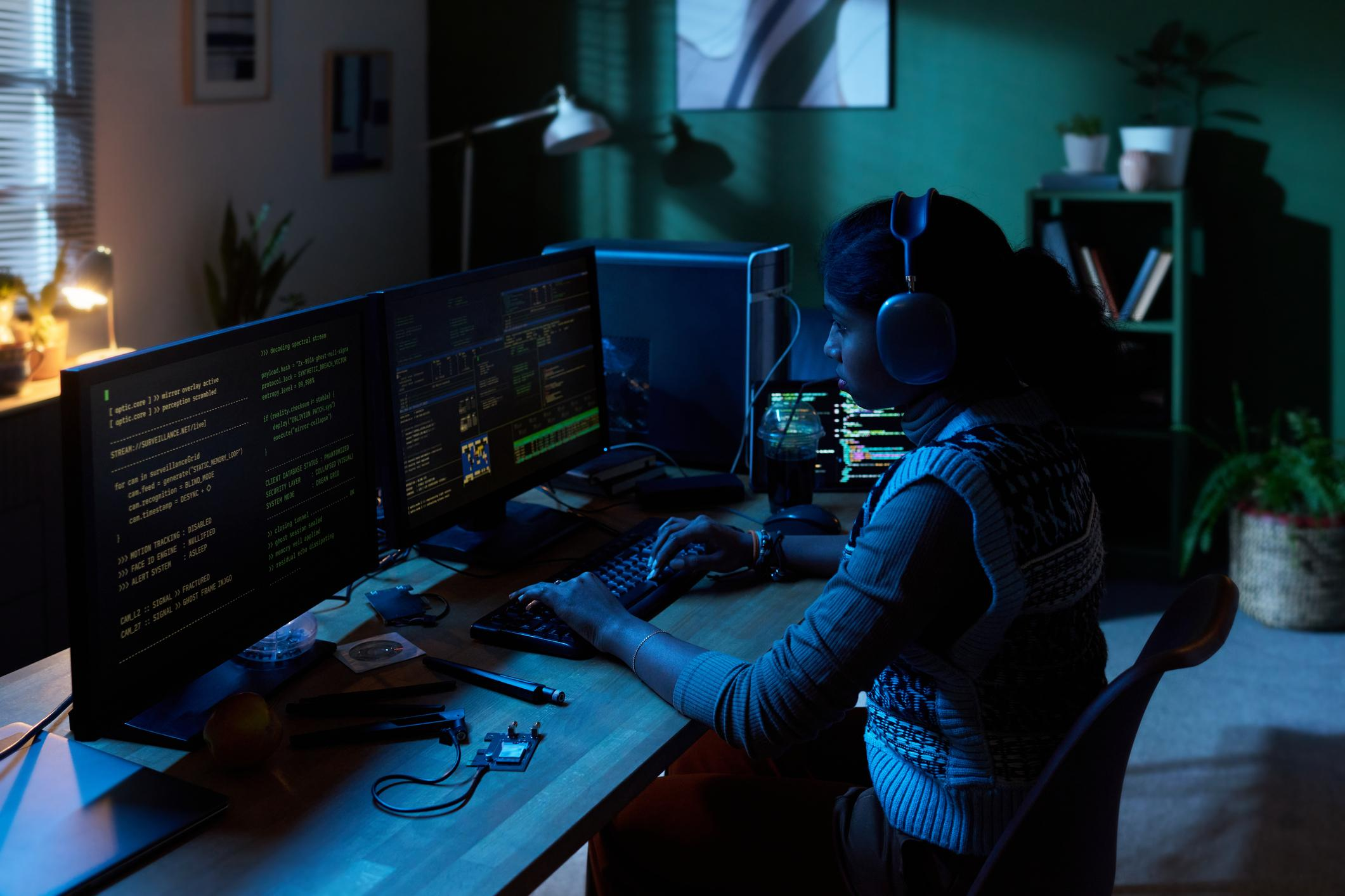 Young Woman Coding Software on Multiple Computer Monitors at Night