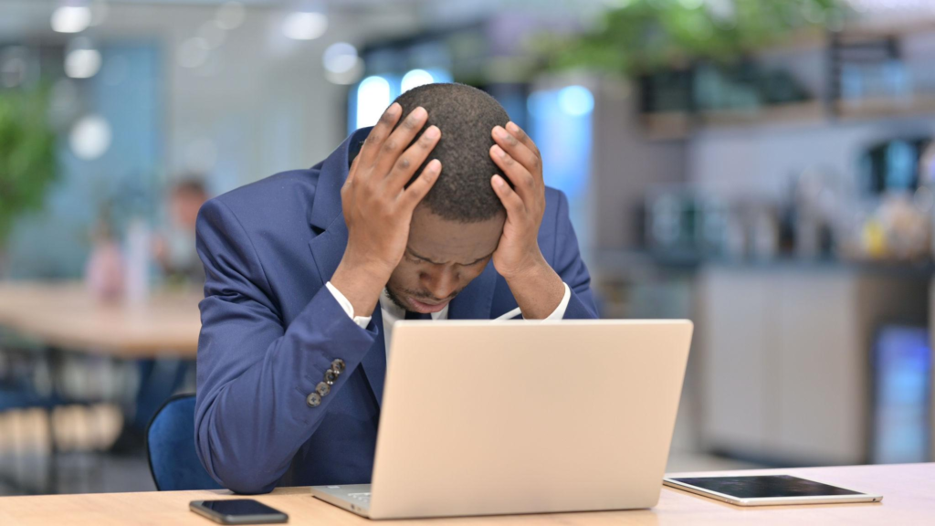 Loss, African Businessman reacting to Failure on Laptop in Office